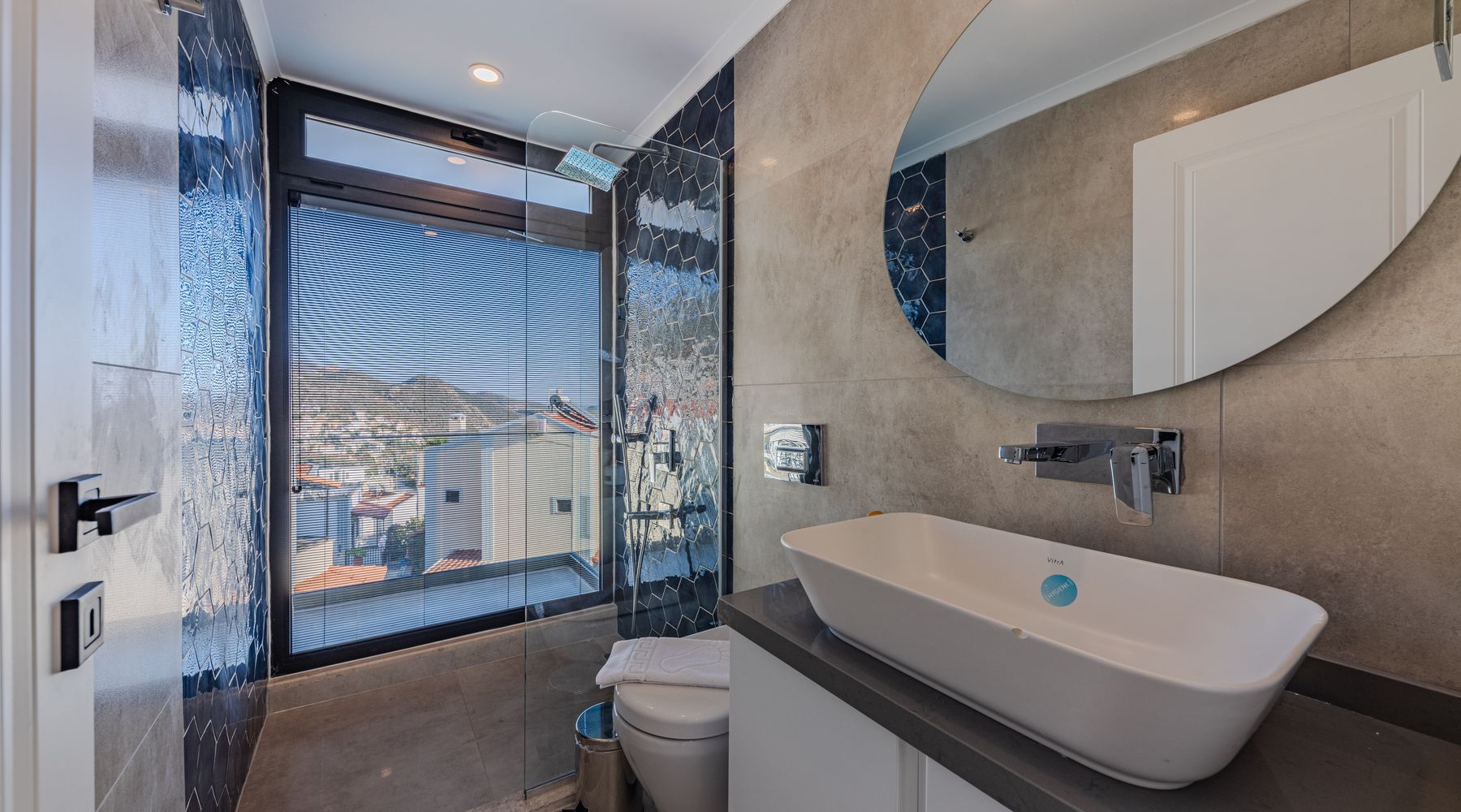 Badezimmer mit blauen Mosaikfliesen, Glasdusche und Aufsatzwaschbecken