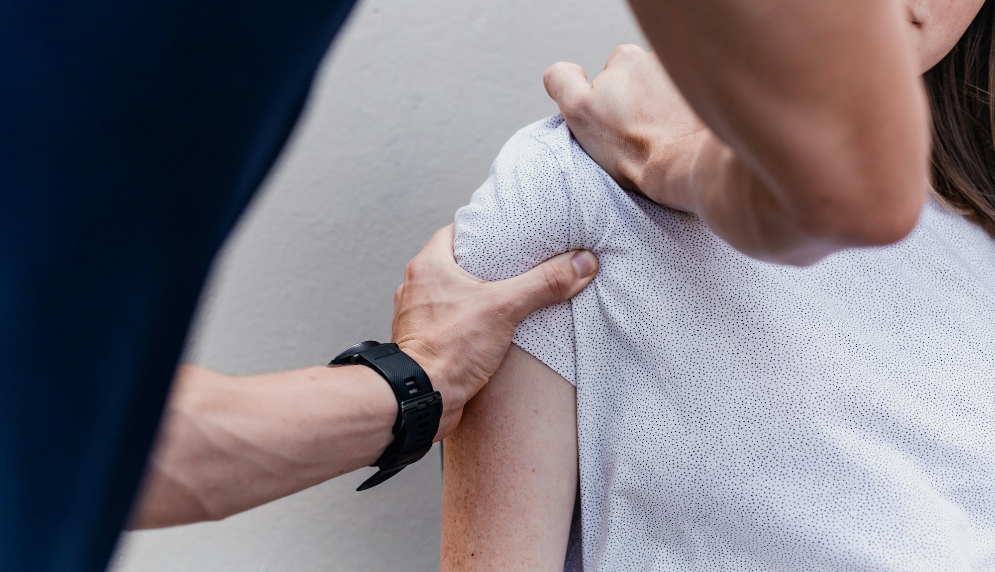 Physiotherapeut untersucht die Schulter einer Patientin